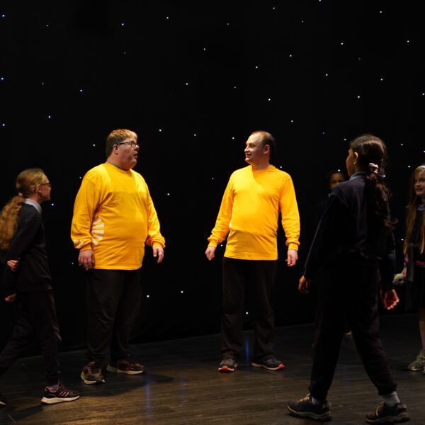 two men wearing yellow long sleeve t-shirts stand facing each other